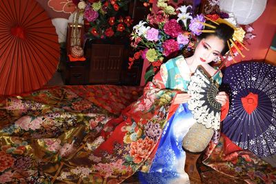 Portrait of young woman wearing traditional clothing holding hand fan