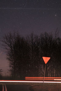 Light trails on road against sky at night