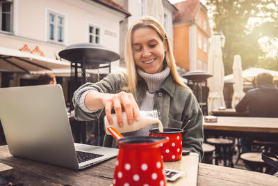 Young woman using mobile phone while sitting on table