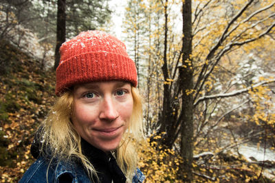 Portrait of young woman standing against trees