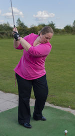 Full length of woman playing golf on field