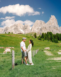 Rear view of couple standing on mountain against sky