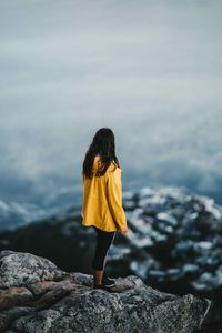 Rear view of woman standing on rock