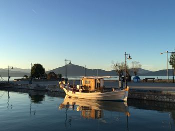 Boats moored in lake against clear blue sky