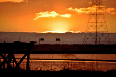 Silhouette electricity pylon against sky during sunset