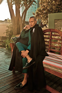 Low angle viw of a man in a stylish suit and coat sitting on the bench