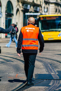 Rear view of man walking on footpath in city