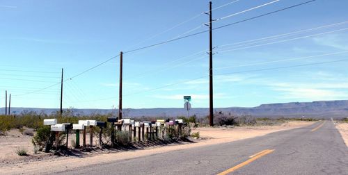 Mailboxes by road against sky