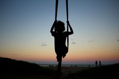 Silhouette of man standing on beach at sunset