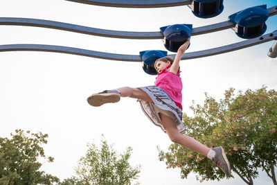 Young girl concentrates swinging her legs on a playground structure