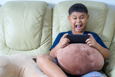 High angle view of boy sitting on sofa