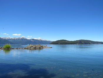 Scenic view of lake against clear blue sky