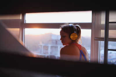 Portrait of woman looking through window at home