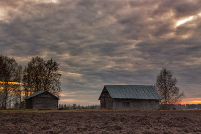 Houses on field against cloudy sky