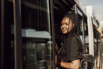 Portrait of smiling young woman standing on train