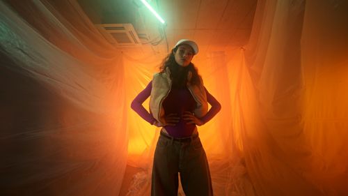 Rear view of woman standing against orange sky