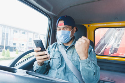 Full length of man using mobile phone in bus