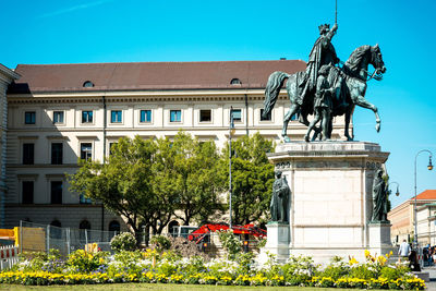 Low angle view of statue by building against sky