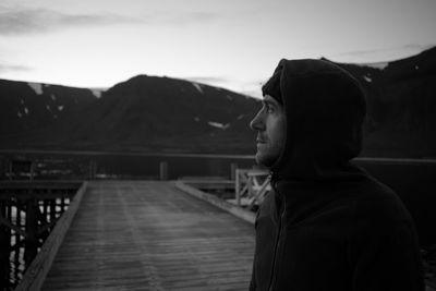 Man looking away while standing on bridge