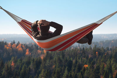 Man relaxing on hammock against forest