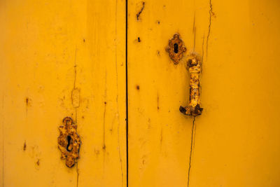 Rusty vintage keyhole on a yellow wooden door