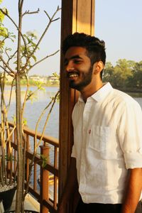 Smiling young man standing by railing