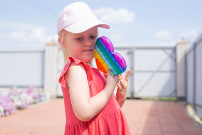 Cute caucasian fair hair girl in pink dress is playing and showing funny trendy silicone antistress 