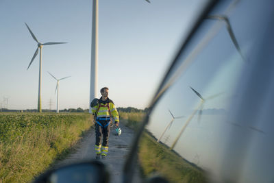 Technician on field path at a wind farm with climbing equipment