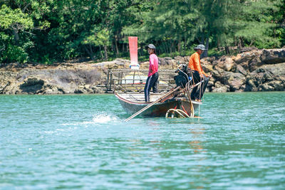 People in boat on river against trees