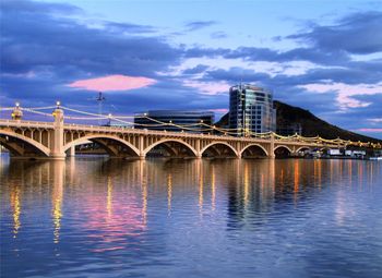 Arch bridge over river against sky in city