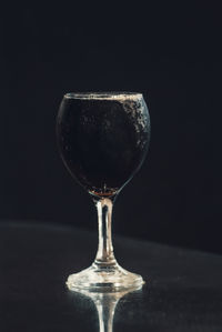 Close-up of wineglass on table against black background