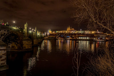 Illuminated bridge over river against sky at night