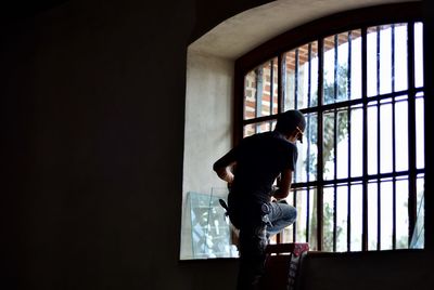 Rear view of woman standing against window