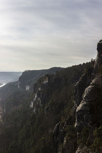 Cliff by sea against sky