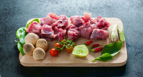 Tomatoes and meat on cutting board over table