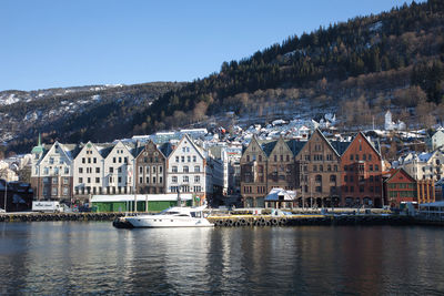 Sailboats by buildings in city against sky