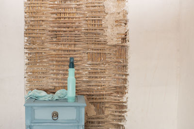 Close-up of man standing against brick wall.  spray and rag on rustic furniture, cleaning