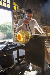 Man working with molten glass using a tweezers in a glass factory