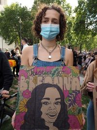 Portrait of young woman standing against plants