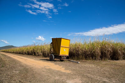 Yellow road amidst field against sky