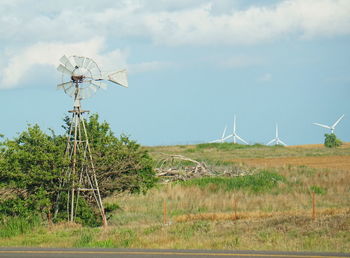 Old windmills on grassy field against sky