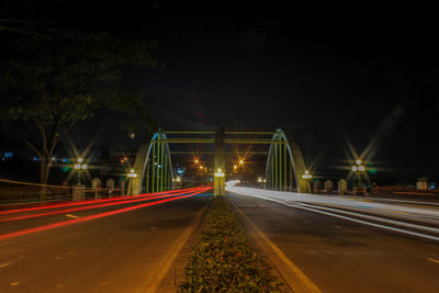 Light trails on road against sky at night