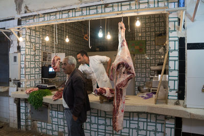 Customer standing by butcher at shop