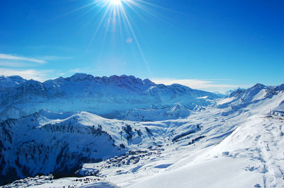 Scenic view of snowcapped mountains against blue sky