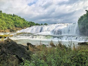 Scenic view of waterfall against sky
