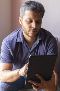 Mid adult man using mobile phone at home