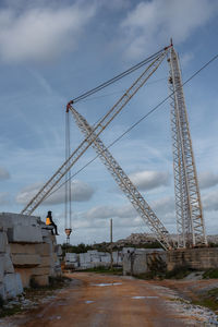 Low angle view of crane at construction site against sky