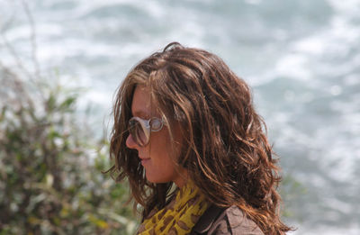 Side view of mid adult woman wearing sunglasses standing against plants