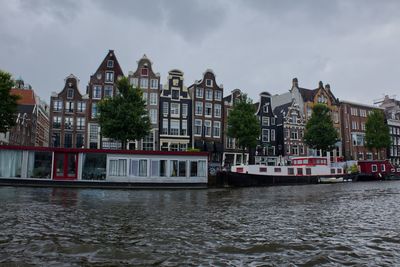 Boats in river against cloudy sky