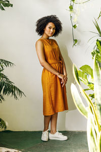 Portrait of young woman standing against wall